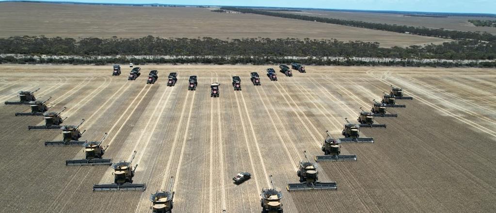 Harversting machines and trucks in V formation in a field