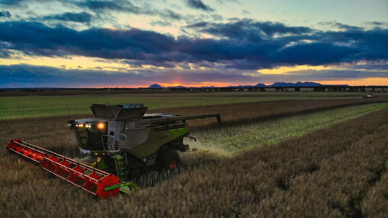 Harvester working in a field with mountains in the background